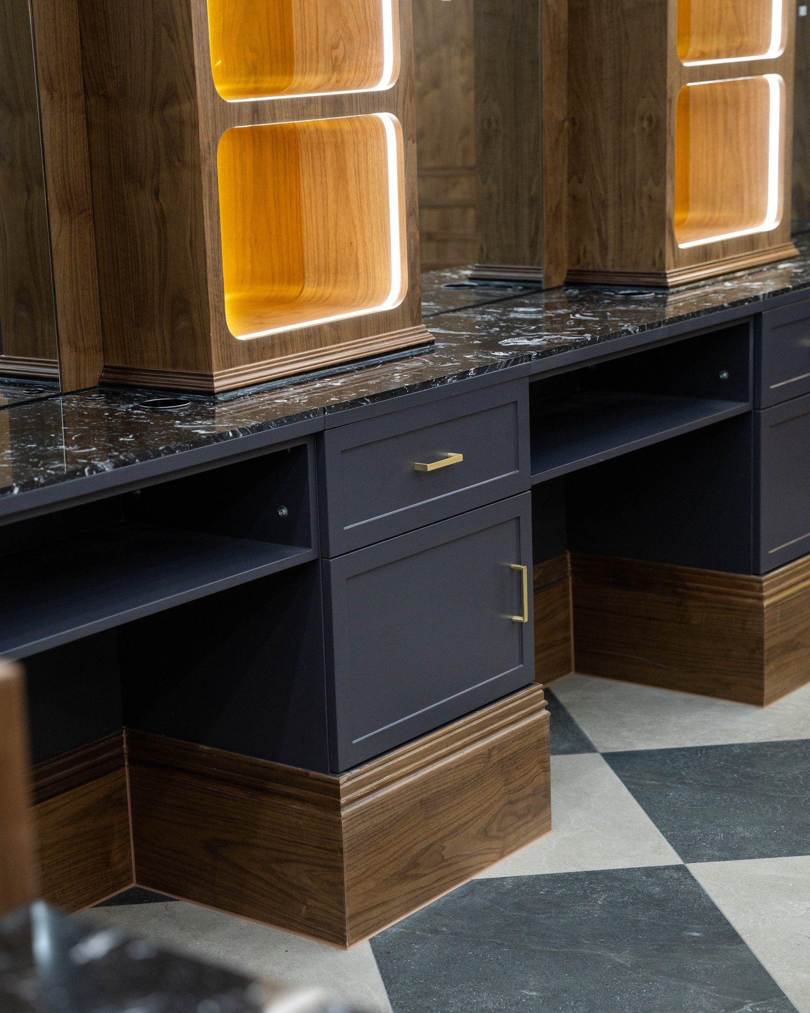 Black marble worktop against brass-lit walnut joinery.