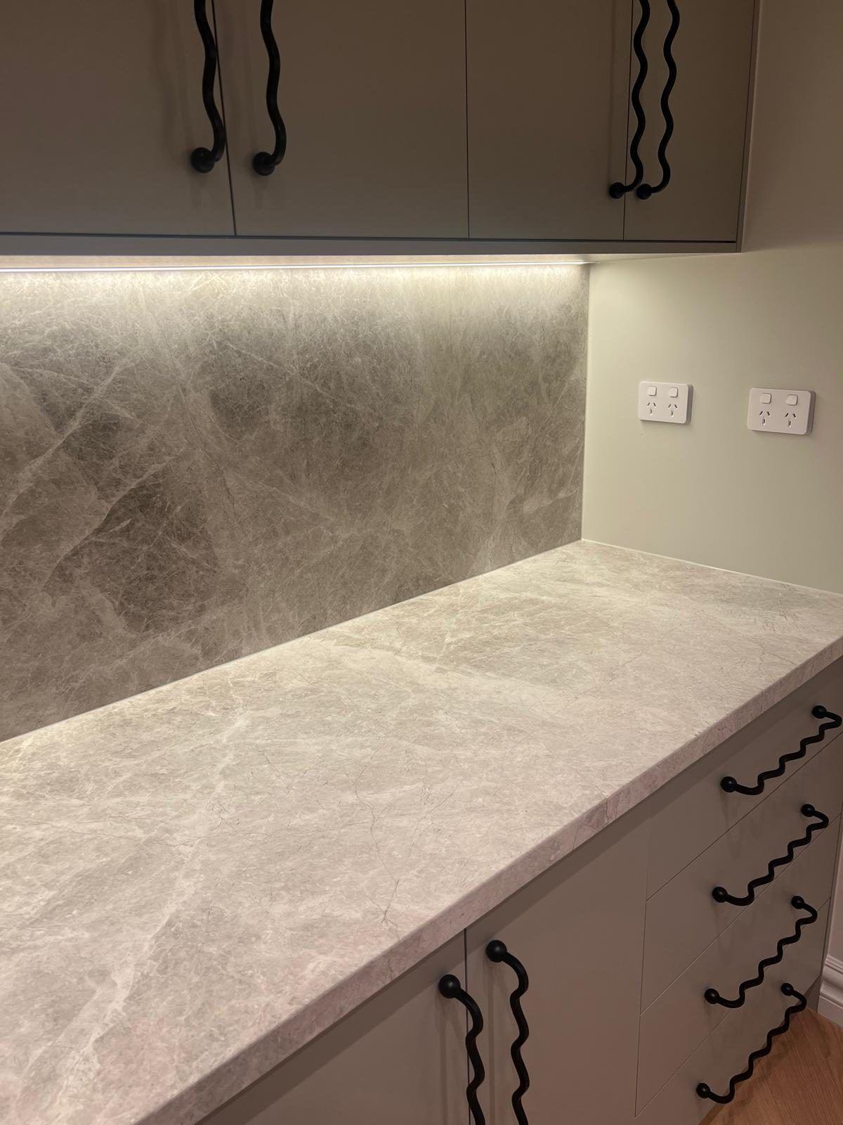 A stone benchtop with wave-form handles below.